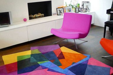 White Living Room with Pink Chair and Colorful Rugs