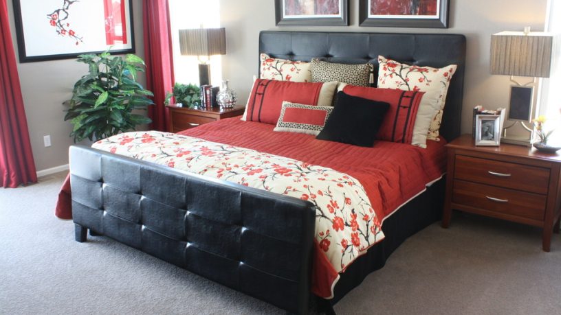 Modern master bedroom with red sheets black bed frame